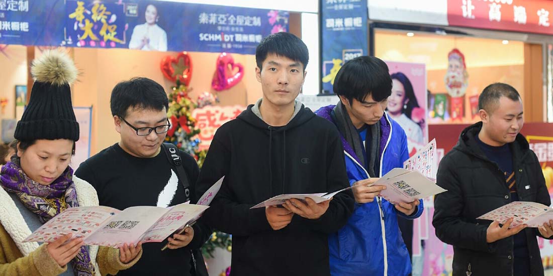 现场消费者驻足活动现场，浏览店铺活动宣传册
